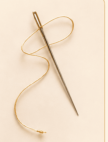 A needle with thread swirled loosely beside it